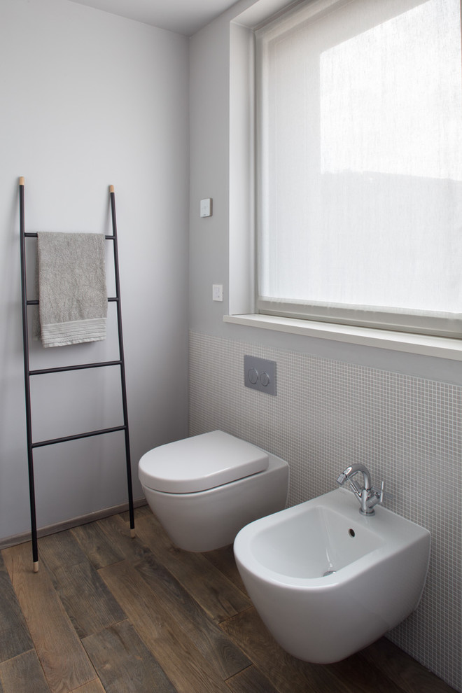 Idee per una stanza da bagno minimal con WC sospeso, piastrelle grigie, piastrelle a mosaico, pareti grigie e parquet scuro
