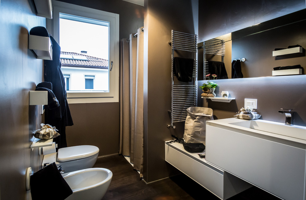 ボローニャにあるコンテンポラリースタイルのおしゃれな浴室 (フラットパネル扉のキャビネット、白いキャビネット、アルコーブ型シャワー、茶色い壁、濃色無垢フローリング、一体型シンク、人工大理石カウンター、シャワーカーテン) の写真