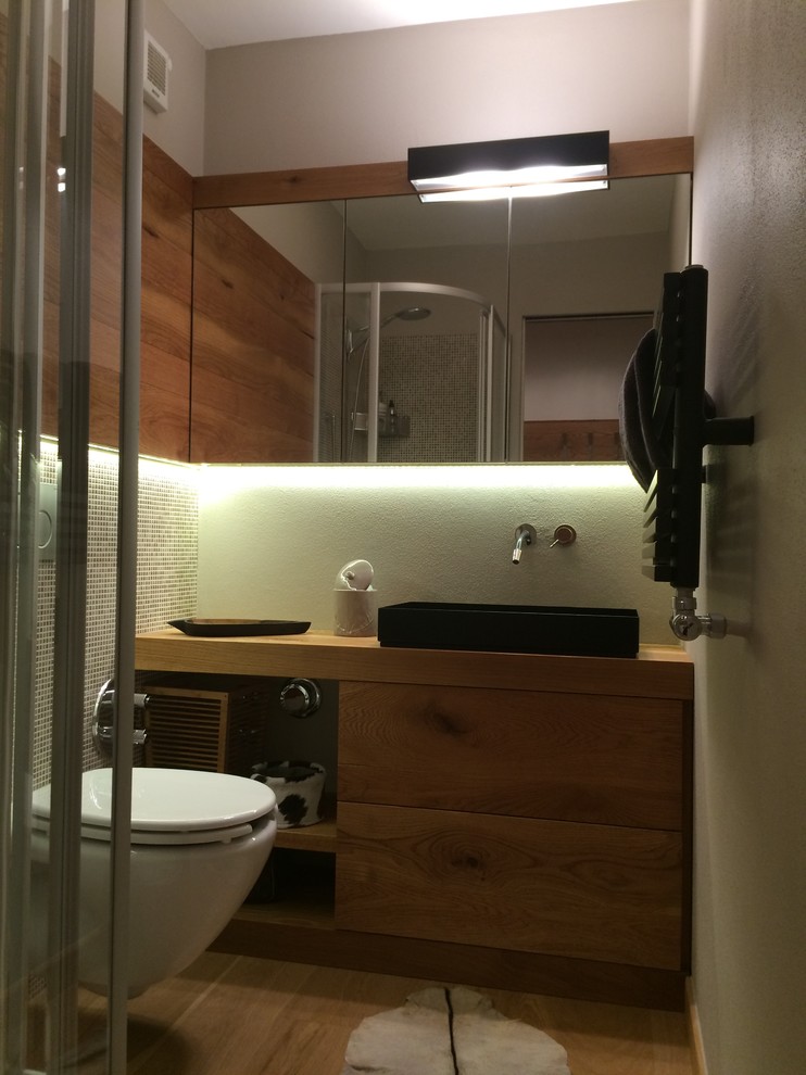 Idéer för ett litet rustikt badrum med dusch, med släta luckor, en hörndusch, en vägghängd toalettstol, grå kakel, porslinskakel, vita väggar, ljust trägolv, ett fristående handfat, träbänkskiva och skåp i ljust trä