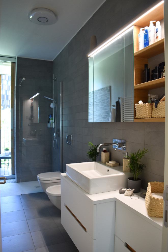 Inspiration for a large contemporary shower room bathroom in Milan with flat-panel cabinets, white cabinets, a built-in shower, a two-piece toilet, grey tiles, porcelain tiles, white walls, porcelain flooring, a vessel sink, solid surface worktops, grey floors, an open shower, white worktops, a single sink and a floating vanity unit.