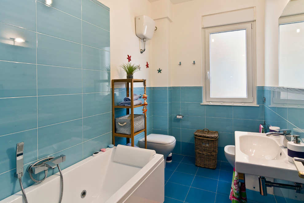 Modelo de cuarto de baño marinero con bañera exenta, baldosas y/o azulejos azules, baldosas y/o azulejos de cerámica, paredes blancas, suelo de baldosas de cerámica y lavabo suspendido