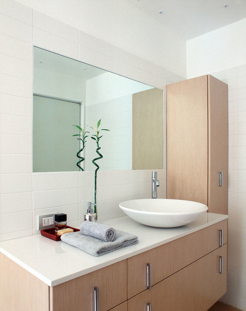 На фото: ванная комната в современном стиле с плоскими фасадами, светлыми деревянными фасадами, белой плиткой, керамической плиткой и настольной раковиной
