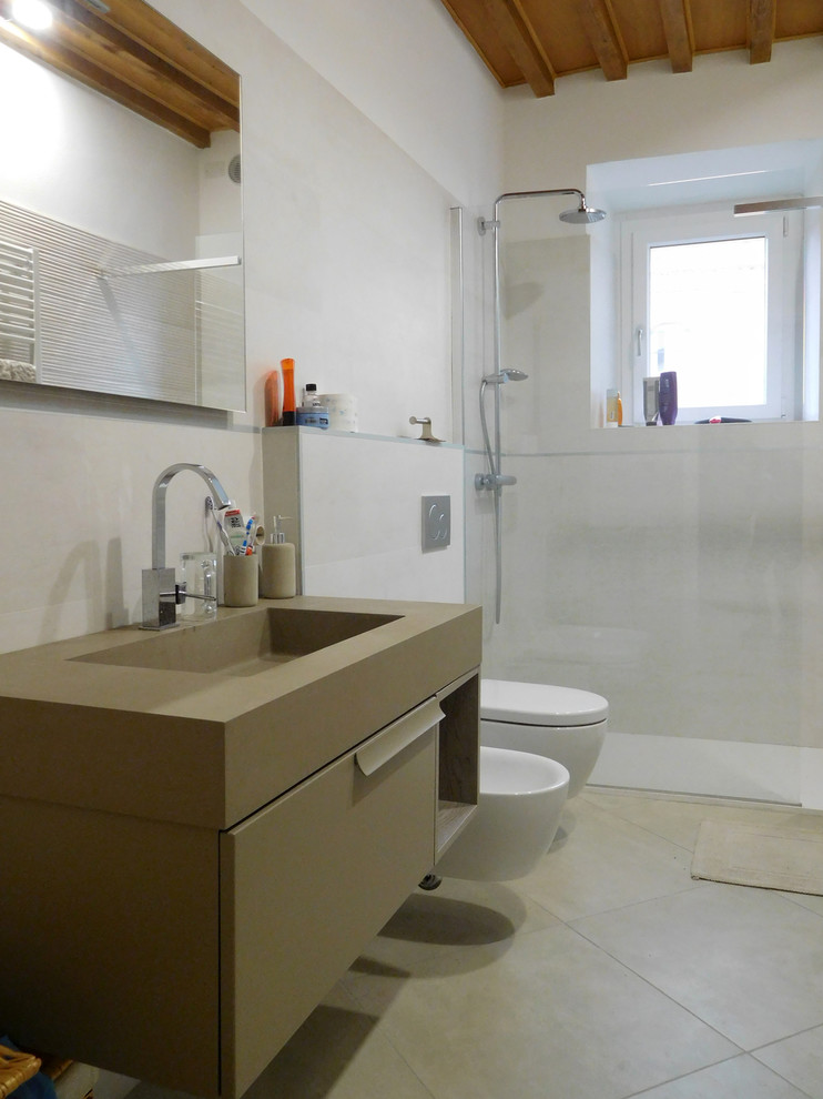 Bild på ett funkis brun brunt badrum, med släta luckor, bruna skåp, en kantlös dusch, en bidé, beige kakel, vita väggar, ett konsol handfat, beiget golv och med dusch som är öppen