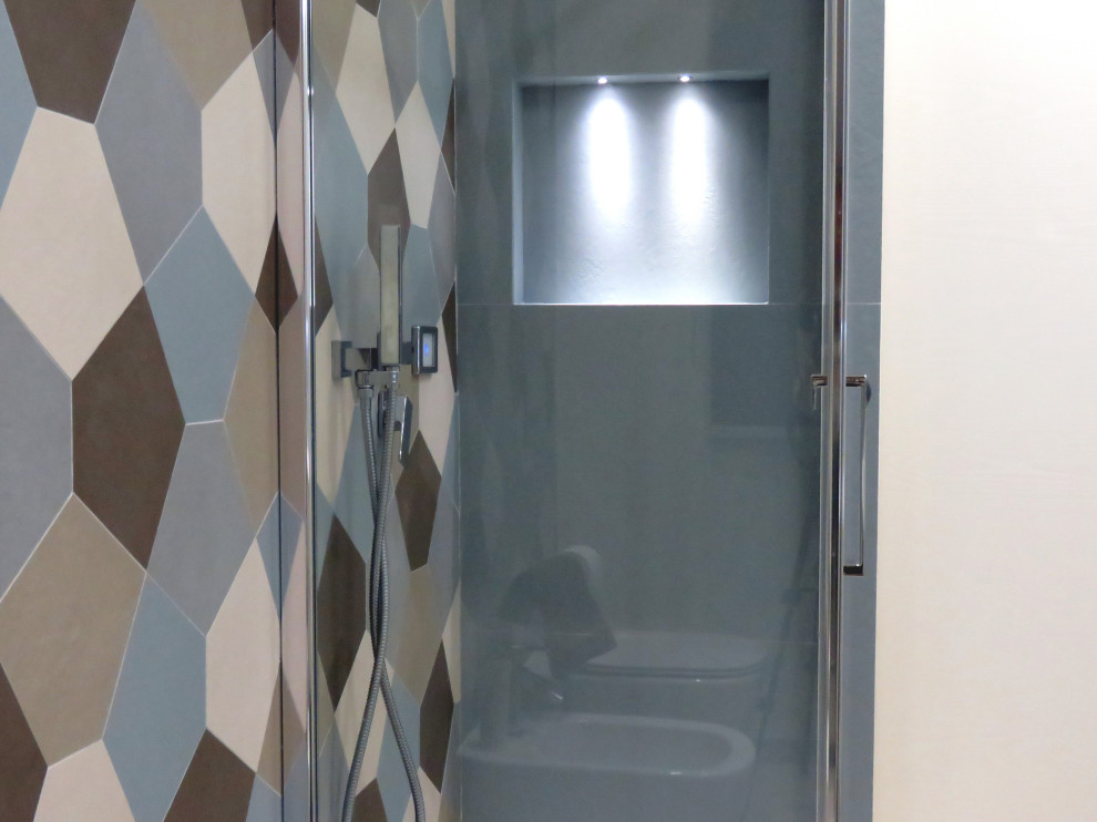 Medium sized contemporary shower room bathroom in Catania-Palermo with flat-panel cabinets, white cabinets, a wall mounted toilet, multi-coloured tiles, ceramic tiles, beige walls, porcelain flooring, an integrated sink, solid surface worktops, beige floors, a hinged door and white worktops.