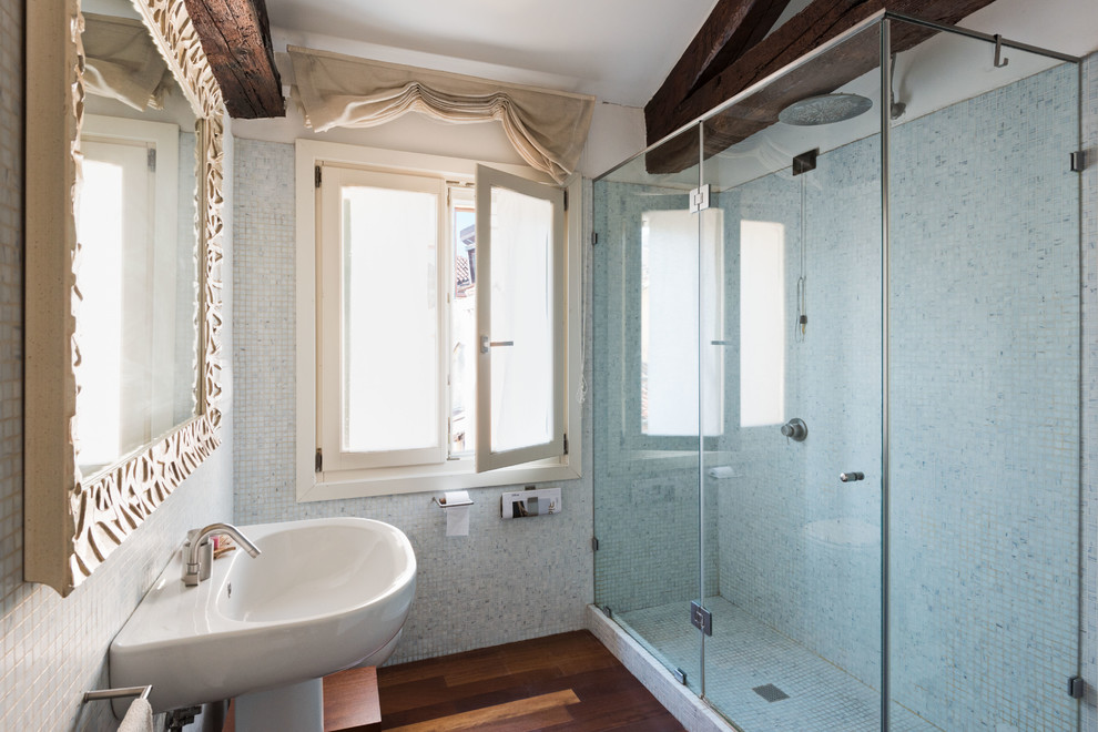Idéer för ett litet medelhavsstil badrum med dusch, med en hörndusch, grå kakel, mosaik, grå väggar, mörkt trägolv, ett piedestal handfat, brunt golv och dusch med gångjärnsdörr