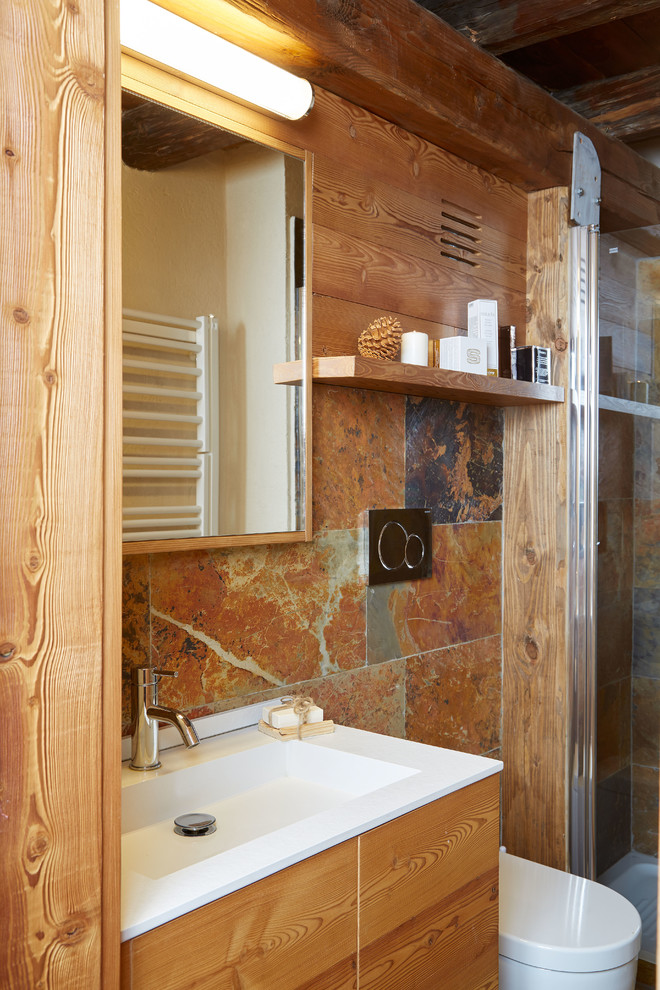 Imagen de cuarto de baño rural pequeño con armarios con paneles lisos, puertas de armario de madera clara, ducha esquinera, sanitario de pared, baldosas y/o azulejos multicolor, suelo de madera clara, aseo y ducha y lavabo encastrado