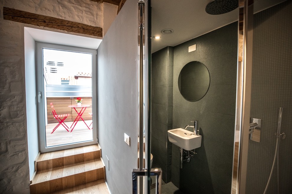 Idéer för mellanstora funkis badrum med dusch, med en kantlös dusch, en vägghängd toalettstol, grön kakel, keramikplattor, vita väggar, ljust trägolv, ett väggmonterat handfat, grönt golv och dusch med gångjärnsdörr