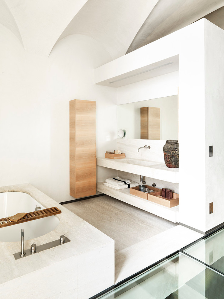 Пример оригинального дизайна: главная ванная комната среднего размера в современном стиле с плоскими фасадами, светлыми деревянными фасадами, накладной ванной, белыми стенами, полом из травертина, монолитной раковиной и плиткой из листового камня