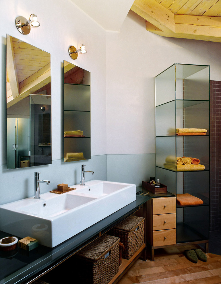 Стильный дизайн: большая ванная комната в современном стиле с стеклянными фасадами, душем без бортиков, инсталляцией, плиткой из листового стекла, светлым паркетным полом, душевой кабиной, раковиной с несколькими смесителями и стеклянной столешницей - последний тренд