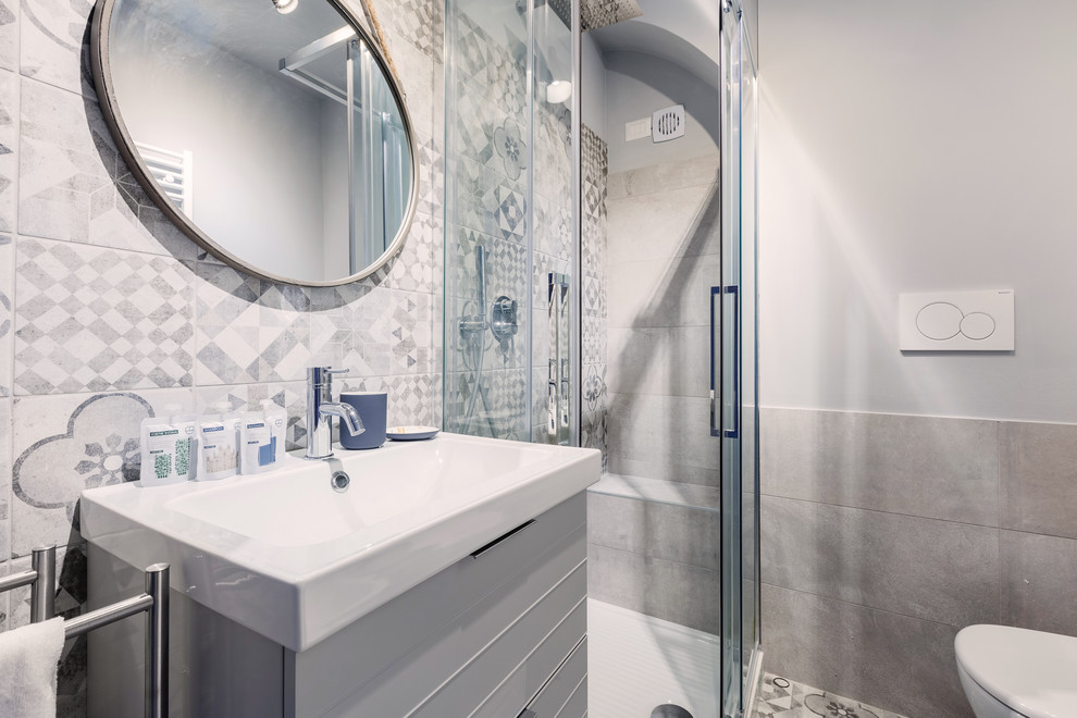 Modern inredning av ett litet vit vitt badrum med dusch, med grå skåp, grå kakel, porslinskakel, grå väggar, cementgolv, ett nedsänkt handfat, bänkskiva i akrylsten, grått golv och dusch med skjutdörr