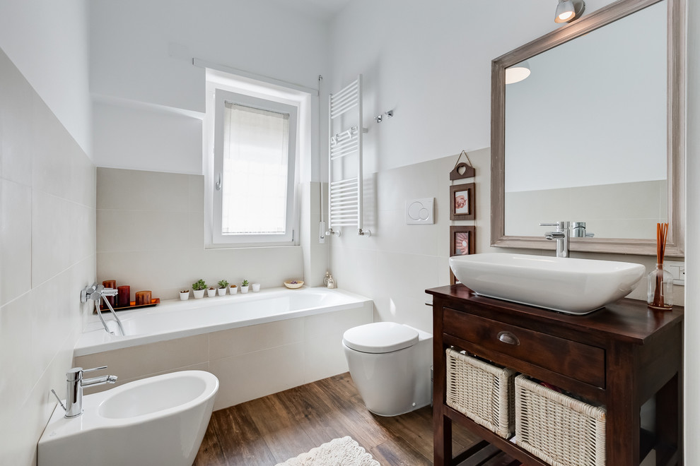 Cette photo montre une salle de bain principale tendance en bois foncé de taille moyenne avec un placard sans porte, une baignoire d'angle, un bidet, un carrelage beige, un mur beige, parquet foncé, une vasque, un plan de toilette en bois et un plan de toilette marron.