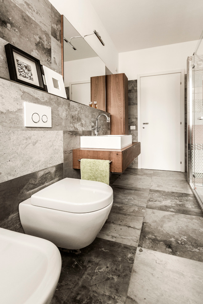 Foto på ett funkis brun badrum med dusch, med vita väggar, marmorgolv, släta luckor, skåp i mellenmörkt trä, en vägghängd toalettstol, träbänkskiva och ett fristående handfat
