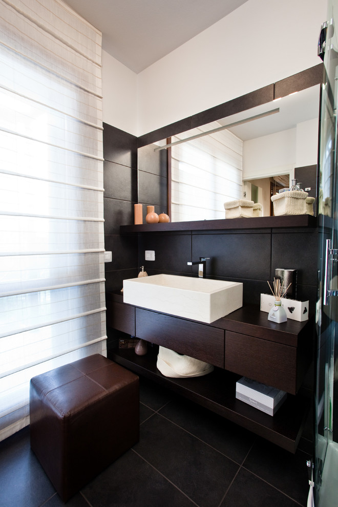 На фото: ванная комната в современном стиле с настольной раковиной, плоскими фасадами, темными деревянными фасадами и черными стенами с