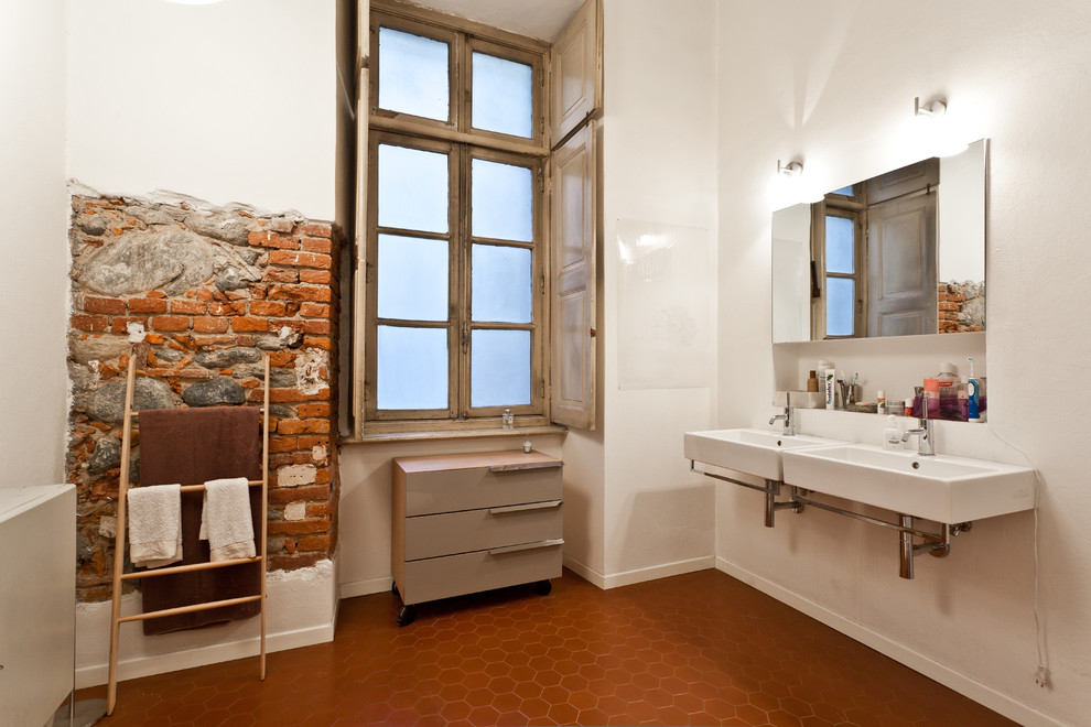 Cette image montre une grande salle de bain design avec un placard à porte plane, des portes de placard beiges, un mur blanc, tomettes au sol et un lavabo suspendu.