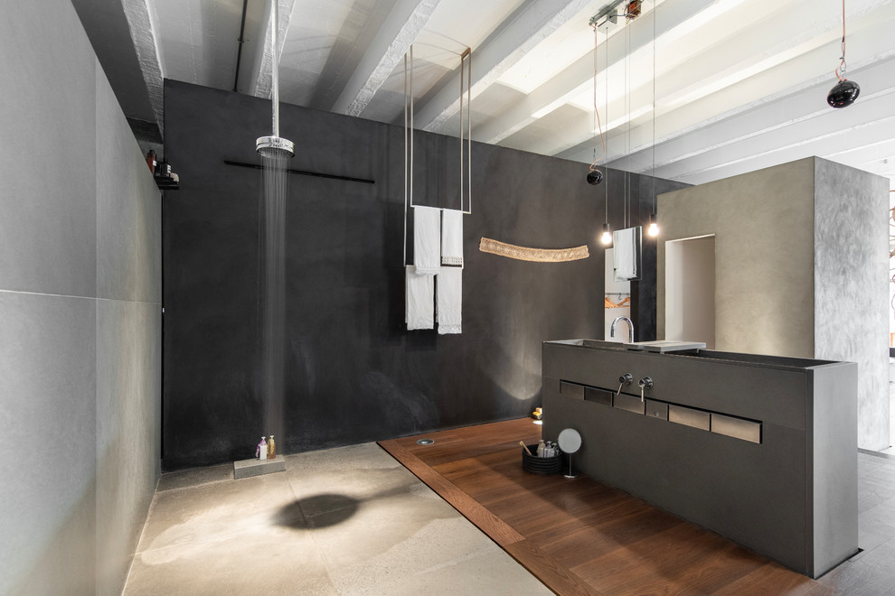 Großes Industrial Duschbad mit grauen Schränken, grauen Fliesen, offener Dusche, offener Dusche, schwarzer Wandfarbe, dunklem Holzboden, Trogwaschbecken und braunem Boden in Mailand
