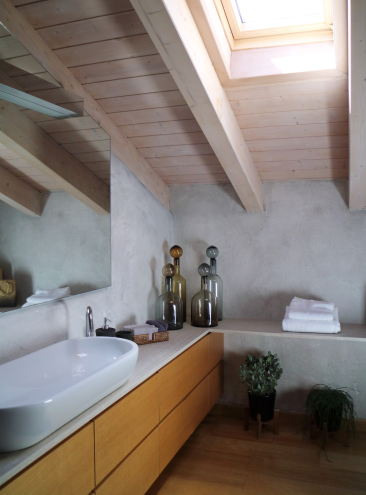 Foto på ett mellanstort funkis badrum med dusch, med skåp i ljust trä, träbänkskiva, luckor med profilerade fronter, en vägghängd toalettstol, grå väggar, ljust trägolv och ett fristående handfat