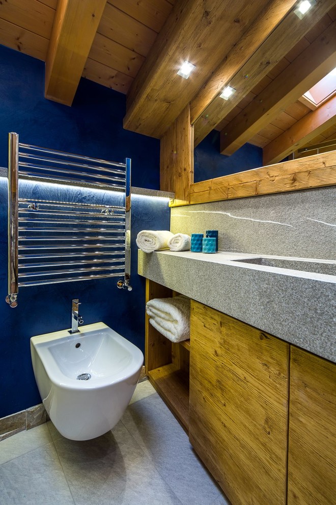 Immagine di una stanza da bagno stile rurale con ante in legno scuro, WC sospeso, lastra di pietra e pareti blu