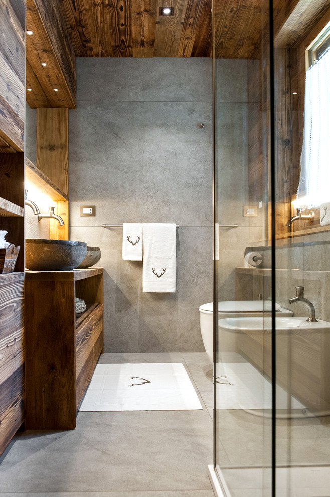 Пример оригинального дизайна: ванная комната среднего размера в стиле рустика с плоскими фасадами, угловым душем, инсталляцией, настольной раковиной, фасадами цвета дерева среднего тона, столешницей из дерева, серой плиткой, керамогранитной плиткой, полом из керамогранита, душевой кабиной, разноцветными стенами и коричневой столешницей