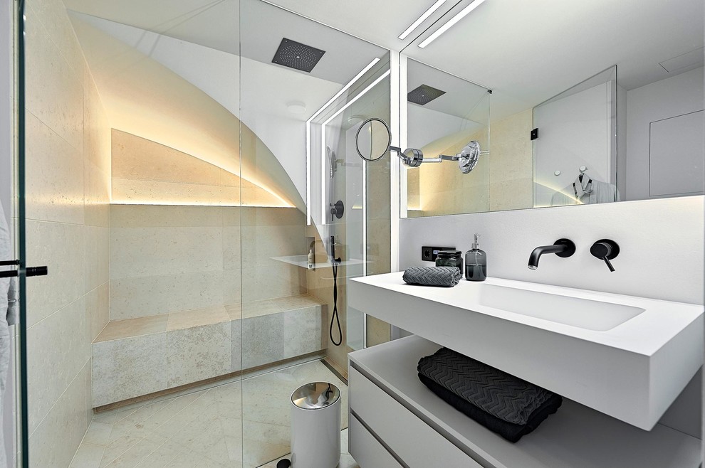 Exempel på ett modernt badrum, med släta luckor, vita skåp, en kantlös dusch, beige kakel, vita väggar, ett väggmonterat handfat och dusch med gångjärnsdörr