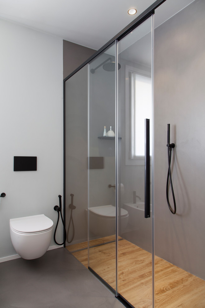 Mittelgroßes Modernes Duschbad mit hellen Holzschränken, bodengleicher Dusche, Wandtoilette, grauen Fliesen, Porzellan-Bodenfliesen, integriertem Waschbecken, Quarzit-Waschtisch, Schiebetür-Duschabtrennung und weißer Waschtischplatte in Mailand
