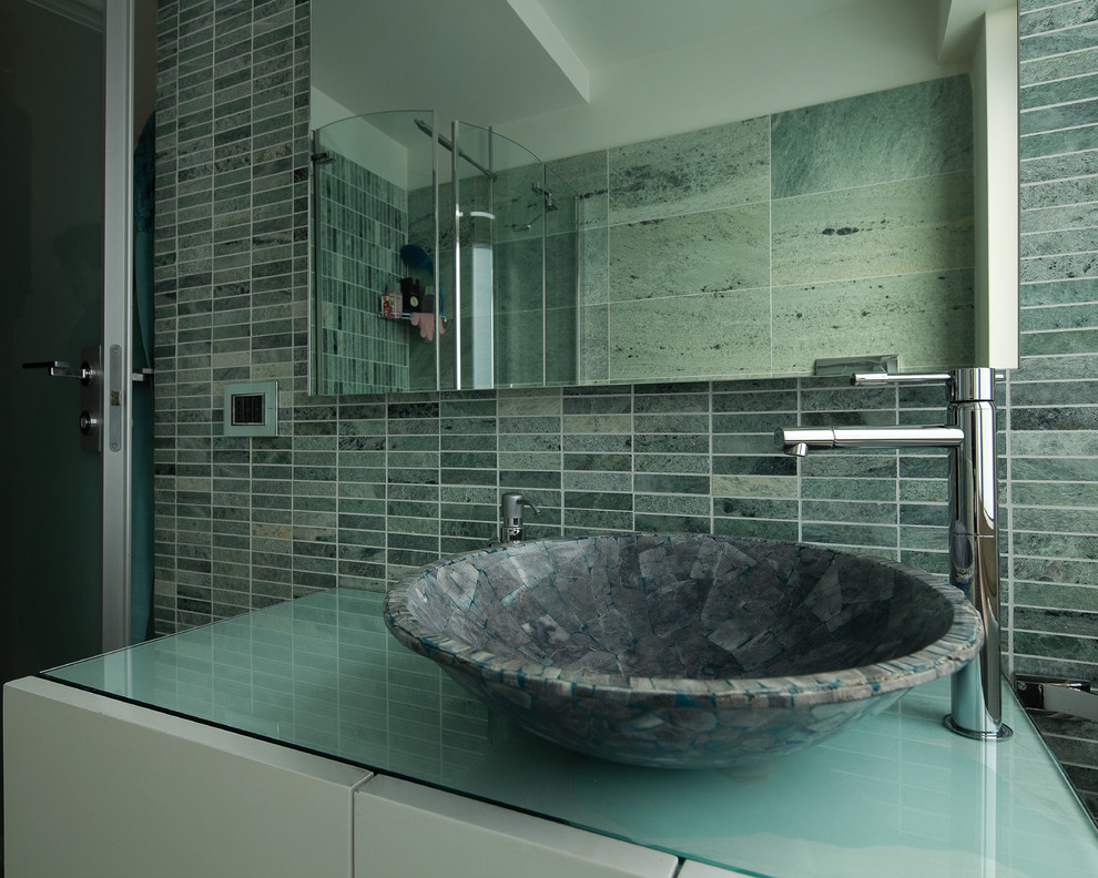 Inredning av ett modernt mellanstort en-suite badrum, med luckor med profilerade fronter, vita skåp, ett japanskt badkar, en hörndusch, en vägghängd toalettstol, grön kakel, marmorkakel, vita väggar, marmorgolv, ett fristående handfat, bänkskiva i glas, grönt golv och dusch med gångjärnsdörr