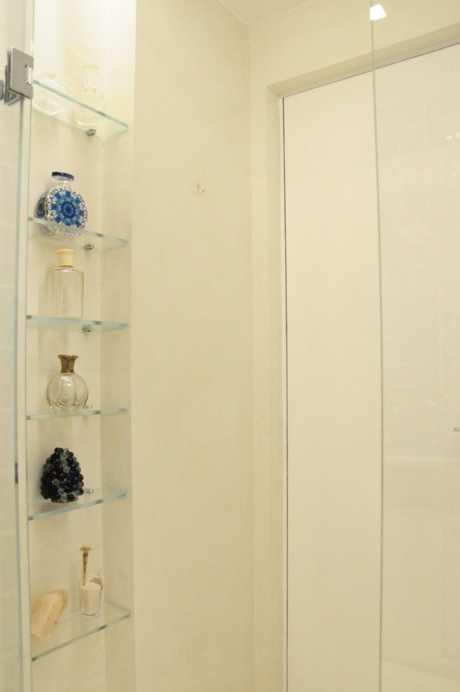 Idéer för att renovera ett mellanstort funkis blå blått en-suite badrum, med släta luckor, blå skåp, en kantlös dusch, betonggolv, vitt golv, dusch med gångjärnsdörr, blå kakel, stenkakel, vita väggar, ett nedsänkt handfat och bänkskiva i kalksten