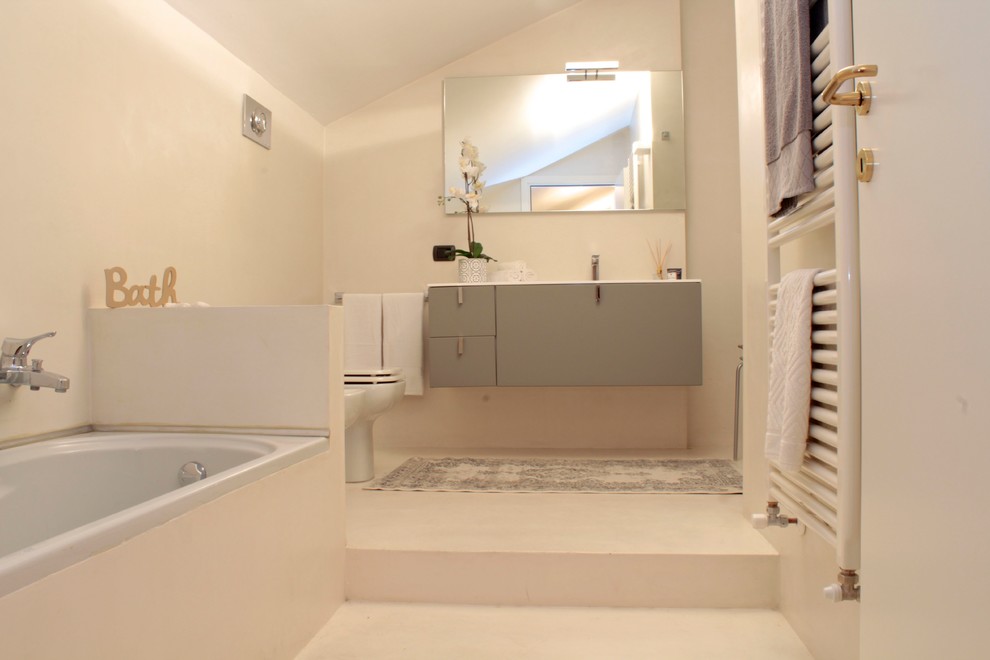 Стильный дизайн: огромная главная ванная комната в стиле модернизм с плоскими фасадами, серыми фасадами, накладной ванной, угловым душем, раздельным унитазом, бежевой плиткой, бежевыми стенами, подвесной раковиной, бежевым полом, белой столешницей и душем с распашными дверями - последний тренд