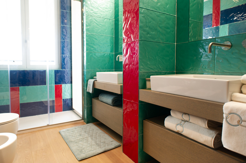 Inspiration för ett mellanstort funkis en-suite badrum, med dusch med skjutdörr, släta luckor, skåp i mellenmörkt trä, en dubbeldusch, grön kakel, glaskakel, ljust trägolv, ett fristående handfat och träbänkskiva