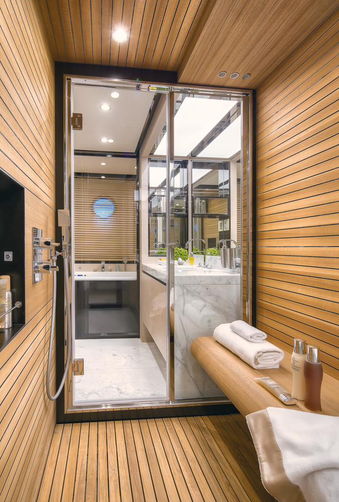Ejemplo de sauna actual con suelo de madera clara, armarios con paneles lisos y encimera de mármol