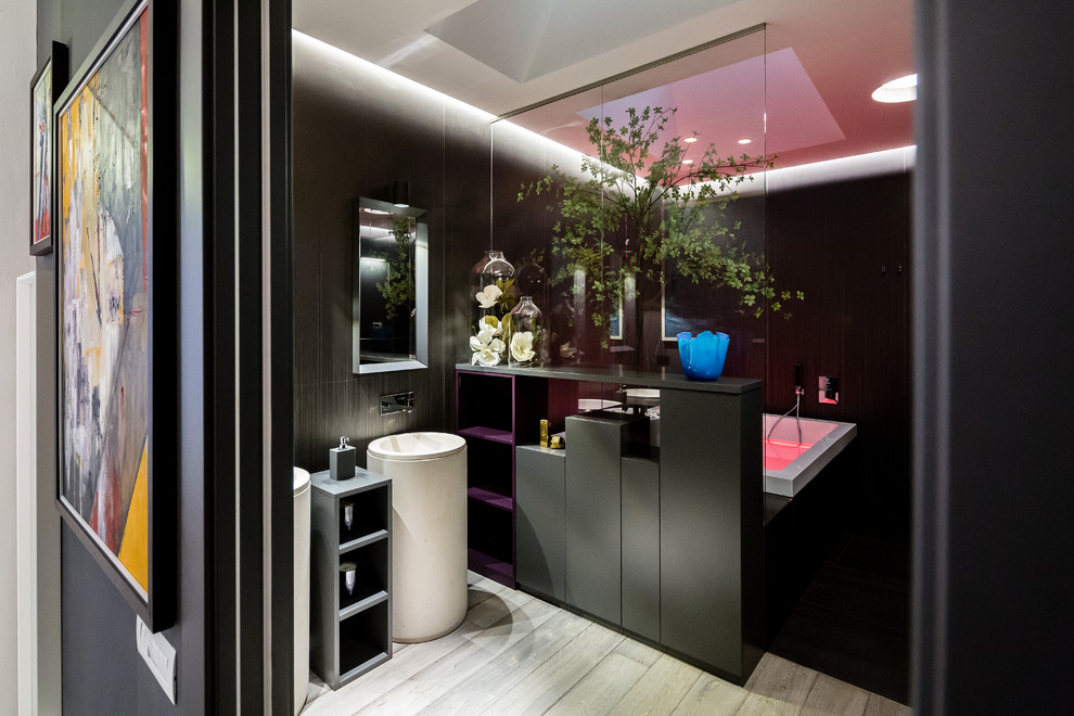 Photo of an expansive bohemian ensuite bathroom in Milan with raised-panel cabinets, black cabinets, a hot tub, a walk-in shower, a wall mounted toilet, black tiles, porcelain tiles, black walls, dark hardwood flooring, a pedestal sink, limestone worktops, grey floors and a sliding door.