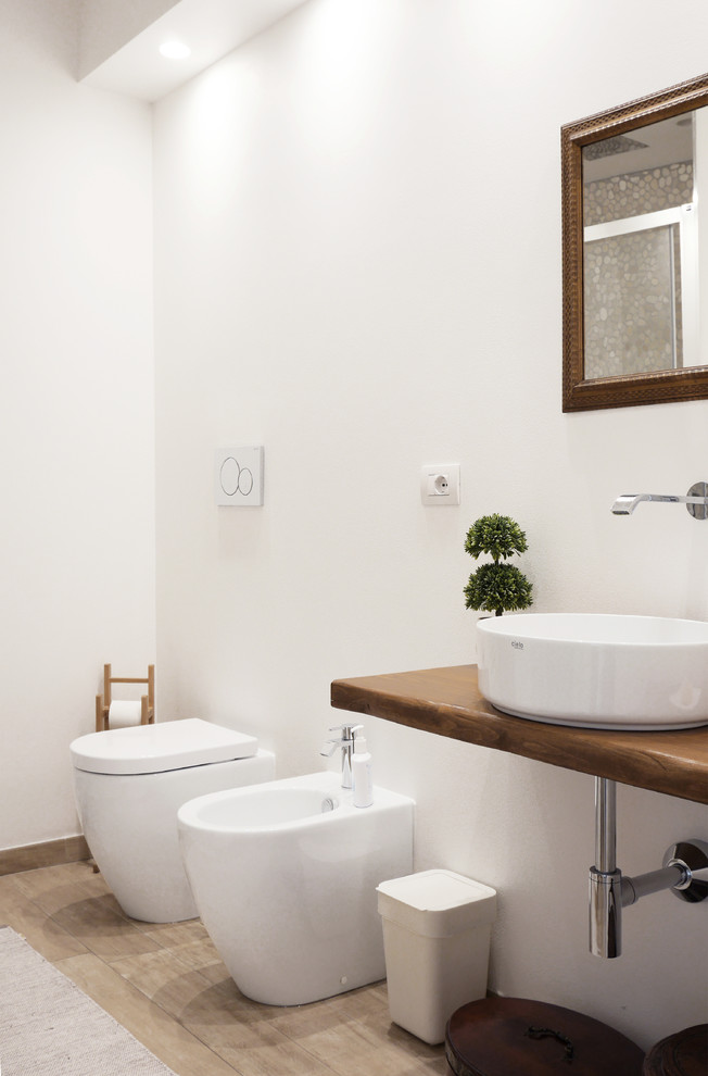 Diseño de cuarto de baño contemporáneo con bidé, paredes blancas, lavabo sobreencimera, encimera de madera, suelo beige y encimeras marrones