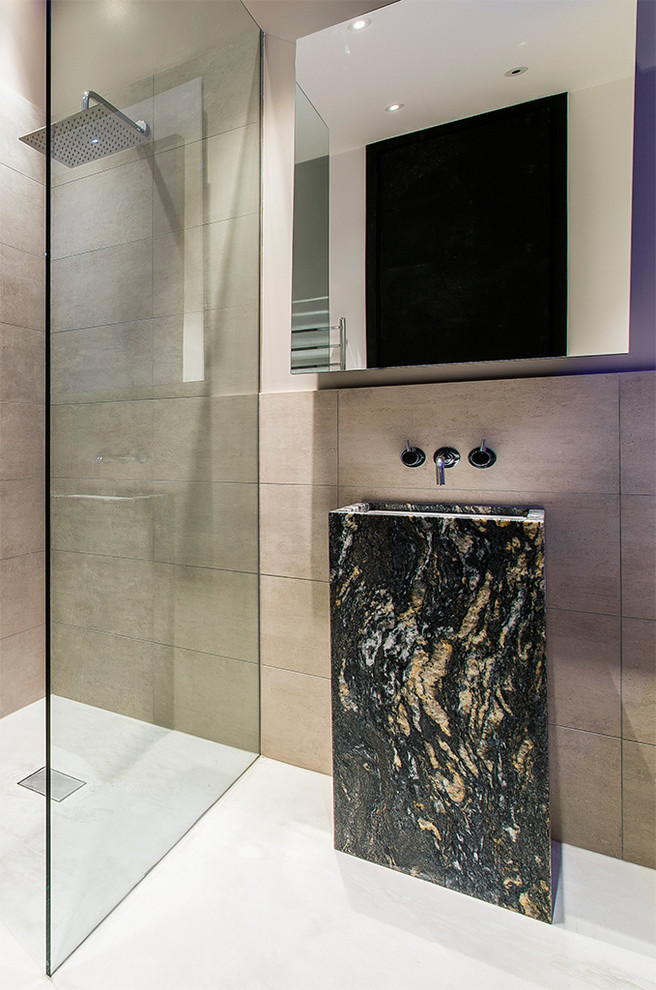 Cette image montre une salle de bain principale minimaliste avec un mur beige, un lavabo de ferme, un plan de toilette en marbre, un plan de toilette noir, une douche à l'italienne, un carrelage marron, un sol beige et aucune cabine.