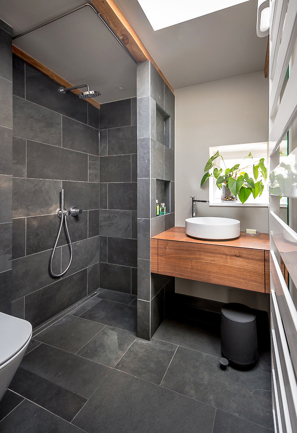 Bild på ett funkis badrum, med svarta skåp, grå kakel, skifferkakel, skiffergolv, träbänkskiva och grått golv