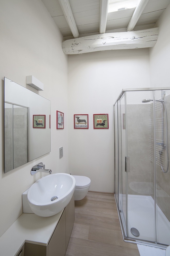 Small contemporary shower room bathroom in Milan with flat-panel cabinets, grey cabinets, a corner shower, a wall mounted toilet, grey tiles, porcelain tiles, white walls, light hardwood flooring, a vessel sink, solid surface worktops and a single sink.
