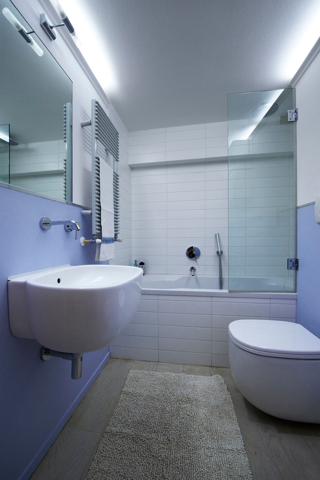 Photo of a small contemporary ensuite bathroom in Milan with a built-in bath, a wall mounted toilet, ceramic tiles, grey walls, a vessel sink and medium hardwood flooring.