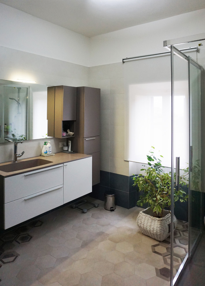На фото: ванная комната среднего размера в современном стиле с плоскими фасадами, бежевыми фасадами, угловым душем, раздельным унитазом, разноцветной плиткой, керамической плиткой, белыми стенами, полом из керамогранита, душевой кабиной, монолитной раковиной, столешницей из искусственного камня, бежевым полом и душем с раздвижными дверями