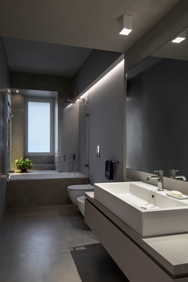 Foto di una stanza da bagno con doccia minimal di medie dimensioni con ante lisce, ante grigie, vasca ad alcova, vasca/doccia, WC sospeso, piastrelle grigie, pareti grigie, lavabo a bacinella, pavimento grigio e top grigio