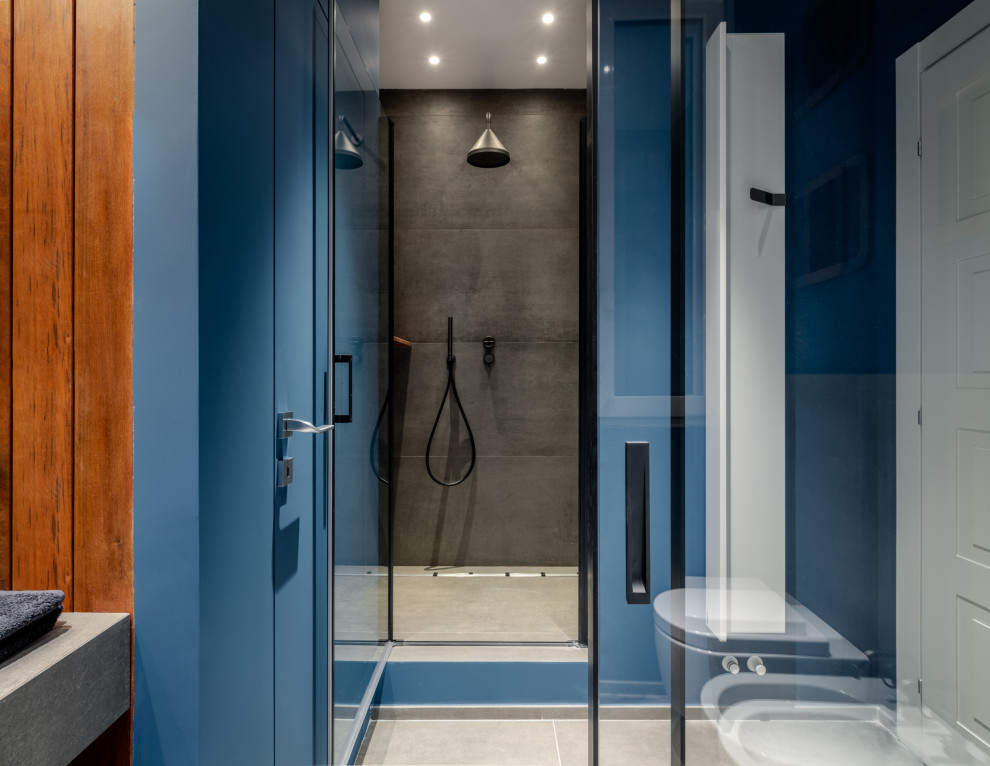 Idéer för ett mellanstort modernt vit badrum med dusch, med öppna hyllor, grå skåp, en dusch i en alkov, en vägghängd toalettstol, beige kakel, porslinskakel, blå väggar, klinkergolv i porslin, ett integrerad handfat, kaklad bänkskiva, grått golv och dusch med gångjärnsdörr