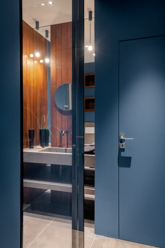 Стильный дизайн: ванная комната среднего размера со стиральной машиной в современном стиле с открытыми фасадами, серыми фасадами, душем в нише, инсталляцией, бежевой плиткой, керамогранитной плиткой, синими стенами, полом из керамогранита, душевой кабиной, монолитной раковиной, столешницей из плитки, серым полом, душем с распашными дверями, белой столешницей, тумбой под одну раковину, подвесной тумбой, многоуровневым потолком и деревянными стенами - последний тренд