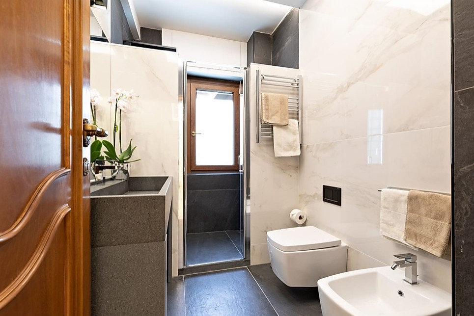 Aménagement d'une grande salle de bain principale contemporaine avec un placard sans porte, des portes de placard grises, une douche double, WC suspendus, un carrelage noir et blanc, des carreaux de porcelaine, un mur blanc, un sol en carrelage de porcelaine, une grande vasque, un plan de toilette en marbre, un sol gris, une cabine de douche à porte battante, un plan de toilette gris, un banc de douche, meuble simple vasque et meuble-lavabo sur pied.