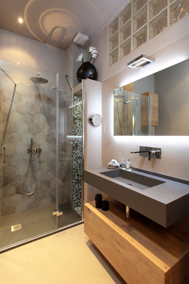 Immagine di una stanza da bagno minimal con lavabo integrato, pareti grigie e porta doccia a battente
