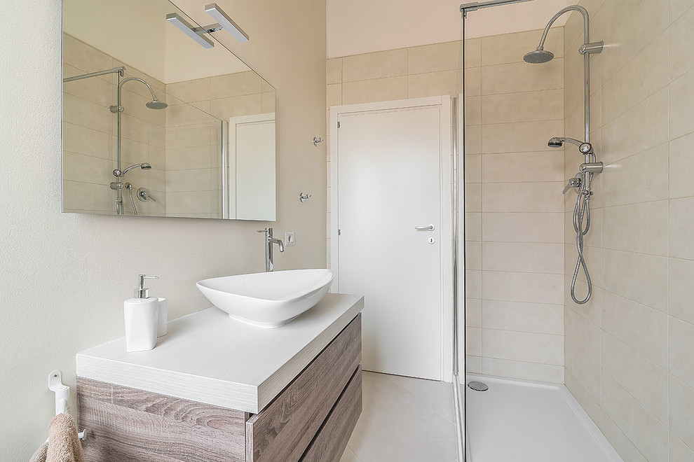 На фото: ванная комната среднего размера в современном стиле с светлыми деревянными фасадами, угловым душем, керамической плиткой, белыми стенами, полом из керамической плитки, душевой кабиной, настольной раковиной, столешницей из дерева, открытым душем и белой столешницей