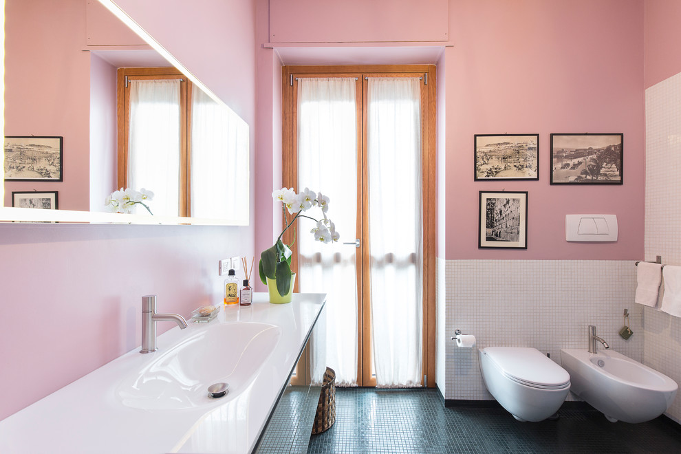 На фото: главная ванная комната среднего размера в современном стиле с накладной ванной, инсталляцией, черной плиткой, плиткой мозаикой, розовыми стенами, монолитной раковиной, стеклянной столешницей, зеленым полом и белой столешницей