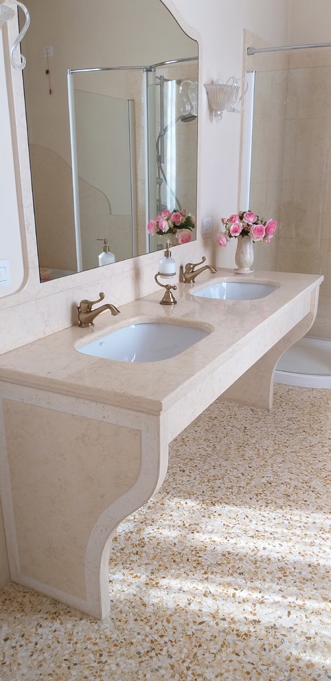Photo of a large traditional bathroom in Milan with a corner bath, an alcove shower, a wall mounted toilet, yellow tiles, marble tiles, yellow walls, terrazzo flooring, a submerged sink, marble worktops, yellow floors, a hinged door and yellow worktops.