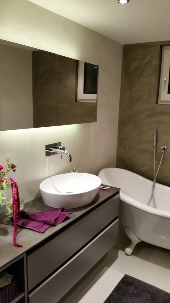 Foto di una stanza da bagno padronale design di medie dimensioni con consolle stile comò, vasca freestanding, WC sospeso, pareti multicolore e lavabo a bacinella