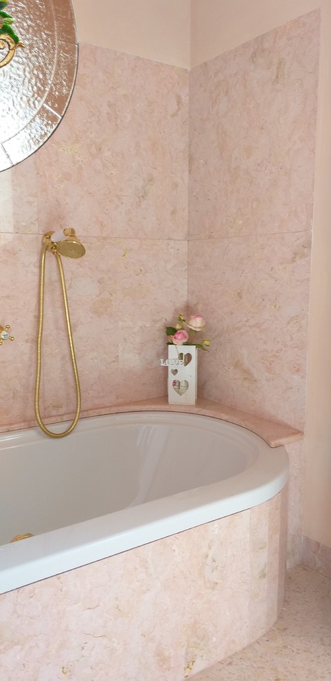 Klassisk inredning av ett stort badrum, med ett platsbyggt badkar, en toalettstol med separat cisternkåpa, rosa kakel, marmorkakel, rosa väggar, ett piedestal handfat och rosa golv