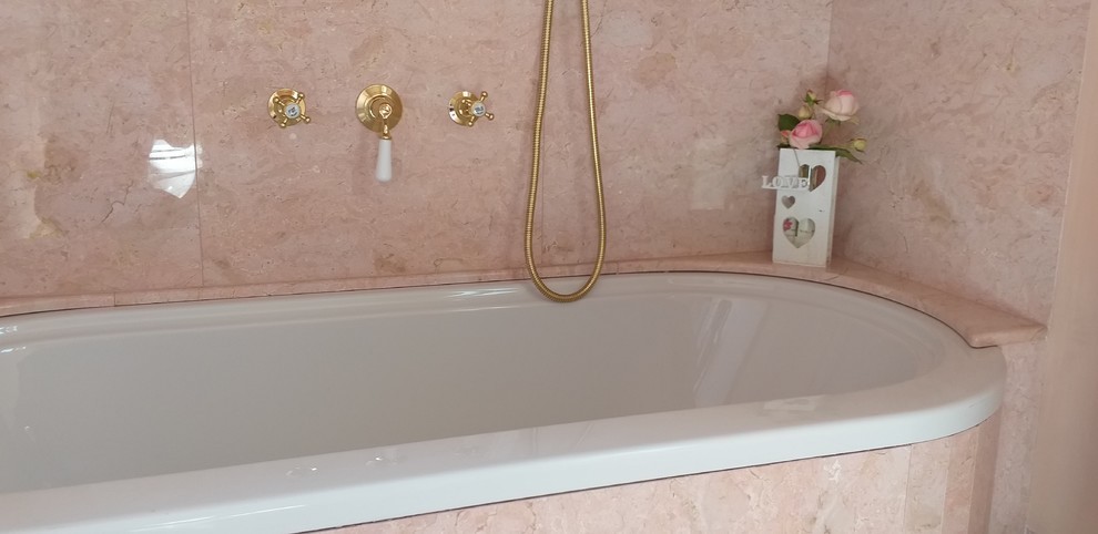 Bild på ett stort vintage badrum, med ett platsbyggt badkar, en toalettstol med separat cisternkåpa, rosa kakel, marmorkakel, rosa väggar, ett piedestal handfat och rosa golv