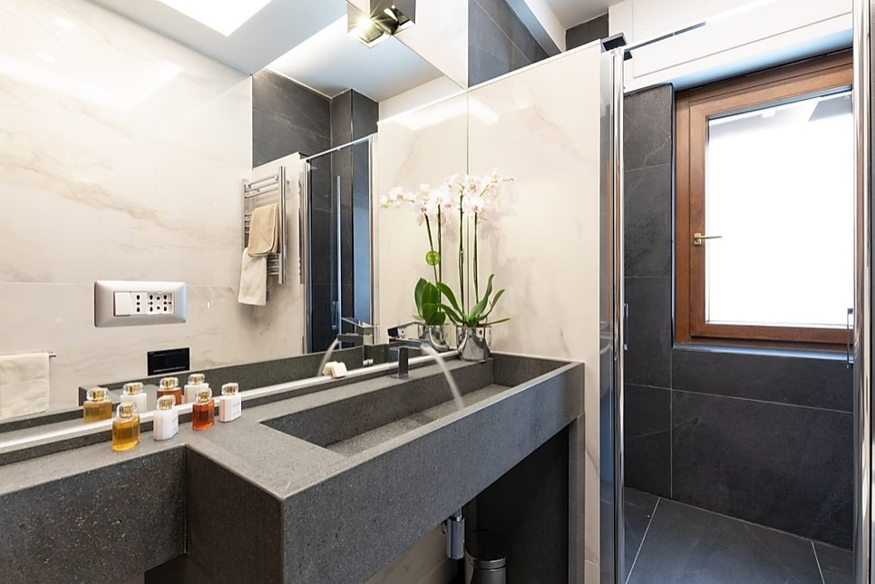 Foto på ett stort funkis grå en-suite badrum, med öppna hyllor, grå skåp, en dubbeldusch, en vägghängd toalettstol, svart och vit kakel, porslinskakel, vita väggar, klinkergolv i porslin, ett avlångt handfat, marmorbänkskiva, grått golv och dusch med gångjärnsdörr