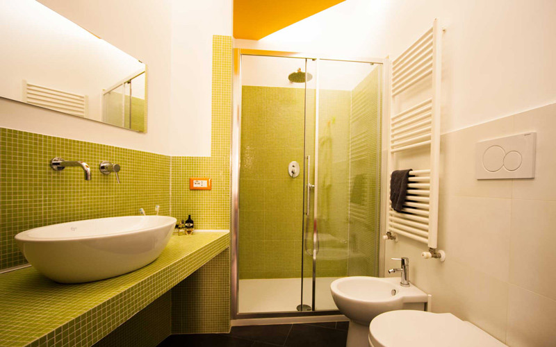 Design ideas for a small modern shower room bathroom in Rome with a built-in shower, a two-piece toilet, green tiles, mosaic tiles, white walls, porcelain flooring, a vessel sink, solid surface worktops, black floors, a sliding door, white worktops, a wall niche, a single sink and a drop ceiling.
