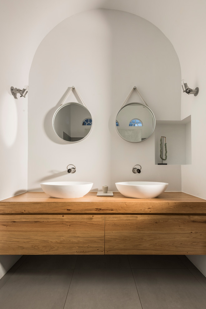 Modernes Badezimmer mit hellbraunen Holzschränken, Waschtisch aus Holz, grauem Boden, flächenbündigen Schrankfronten, weißer Wandfarbe, Aufsatzwaschbecken und beiger Waschtischplatte in Mailand